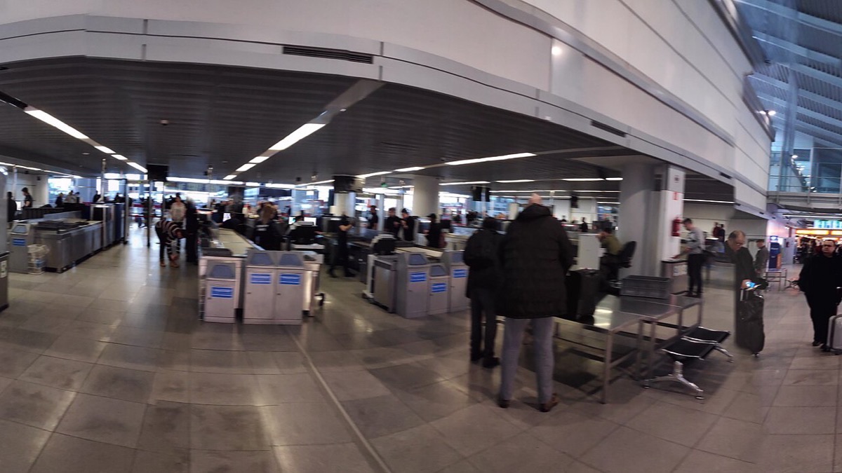 The bright, modern passenger terminal of Warsaw Chopin Airport with check-in areas and signage.