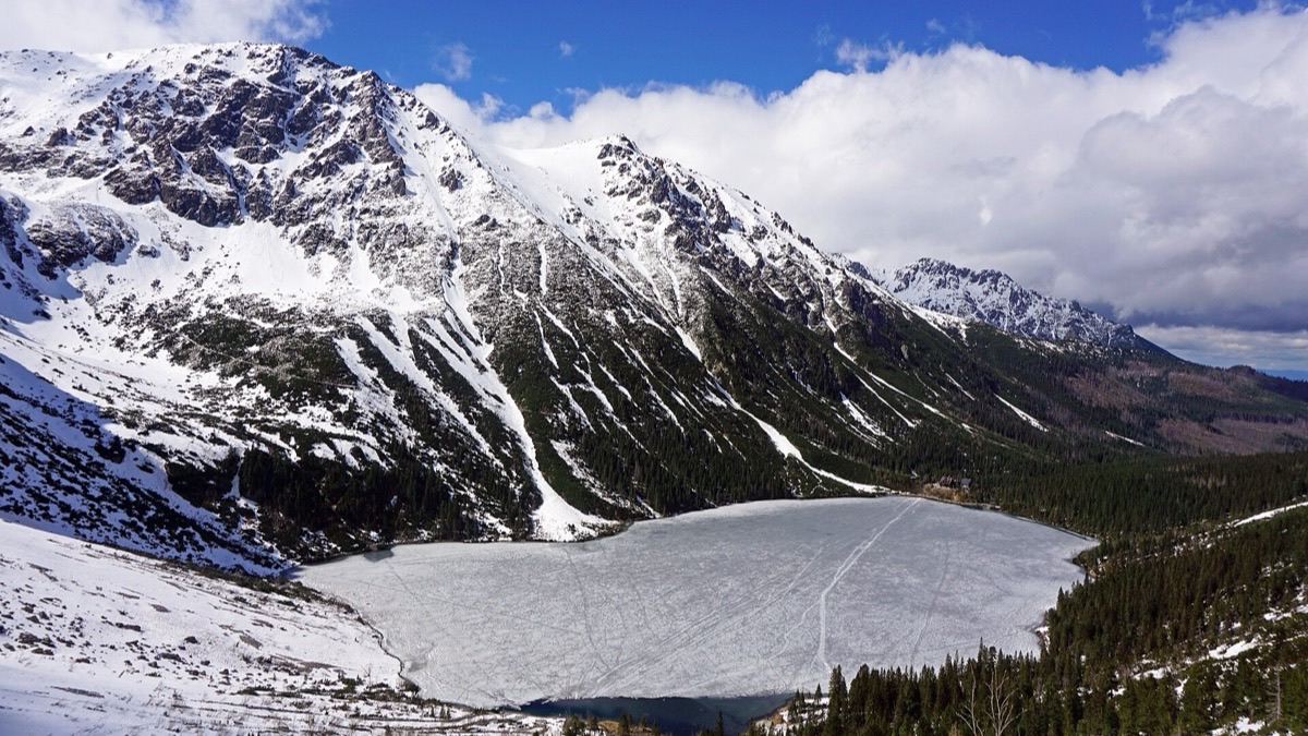 The frozen surface of Morskie Oko lake ringed by snow-covered Tatra mountain peaks.